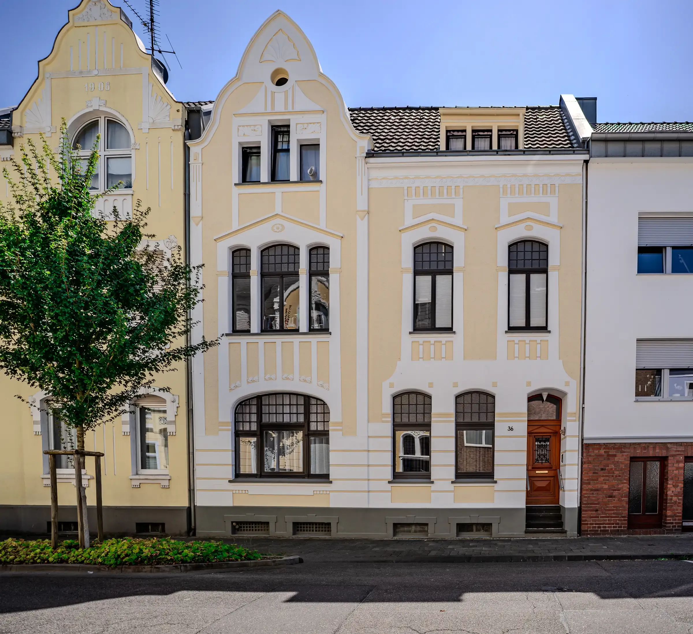 Cremefarbene Gründerzeitfassade mit Stuckgesimsen und geschwungenem Zwerchgiebel