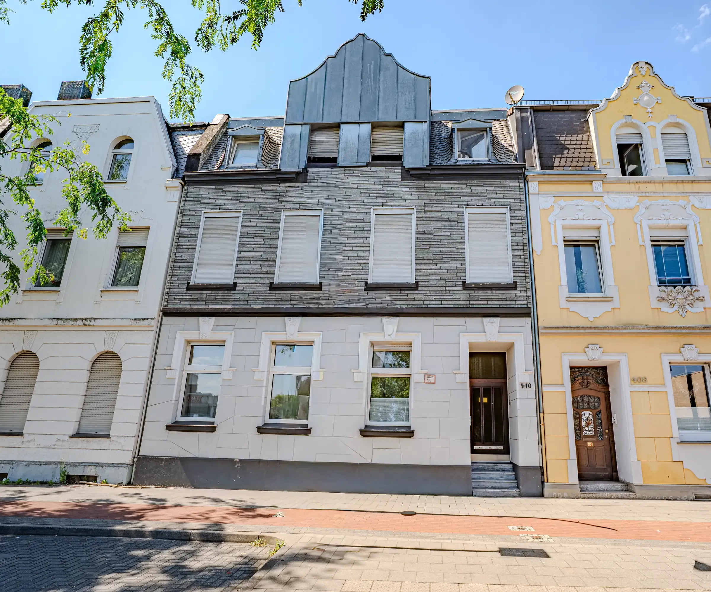 Stadthaus mit heller Putzfassade im Erdgeschoss und dunkler Schieferverkleidung darüber