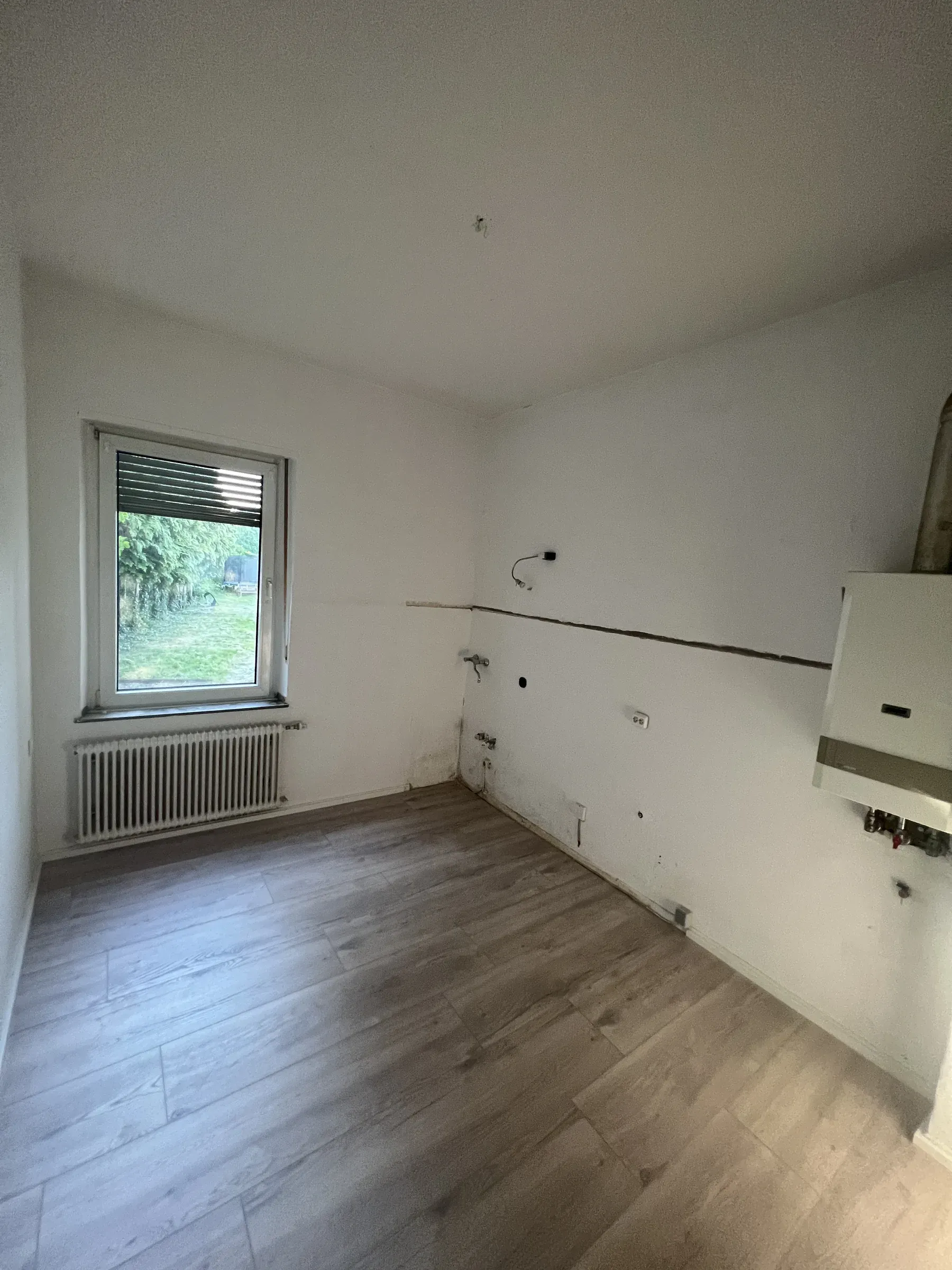 Küche mit vorbereiteten Anschlüssen und Fenster ins Grüne