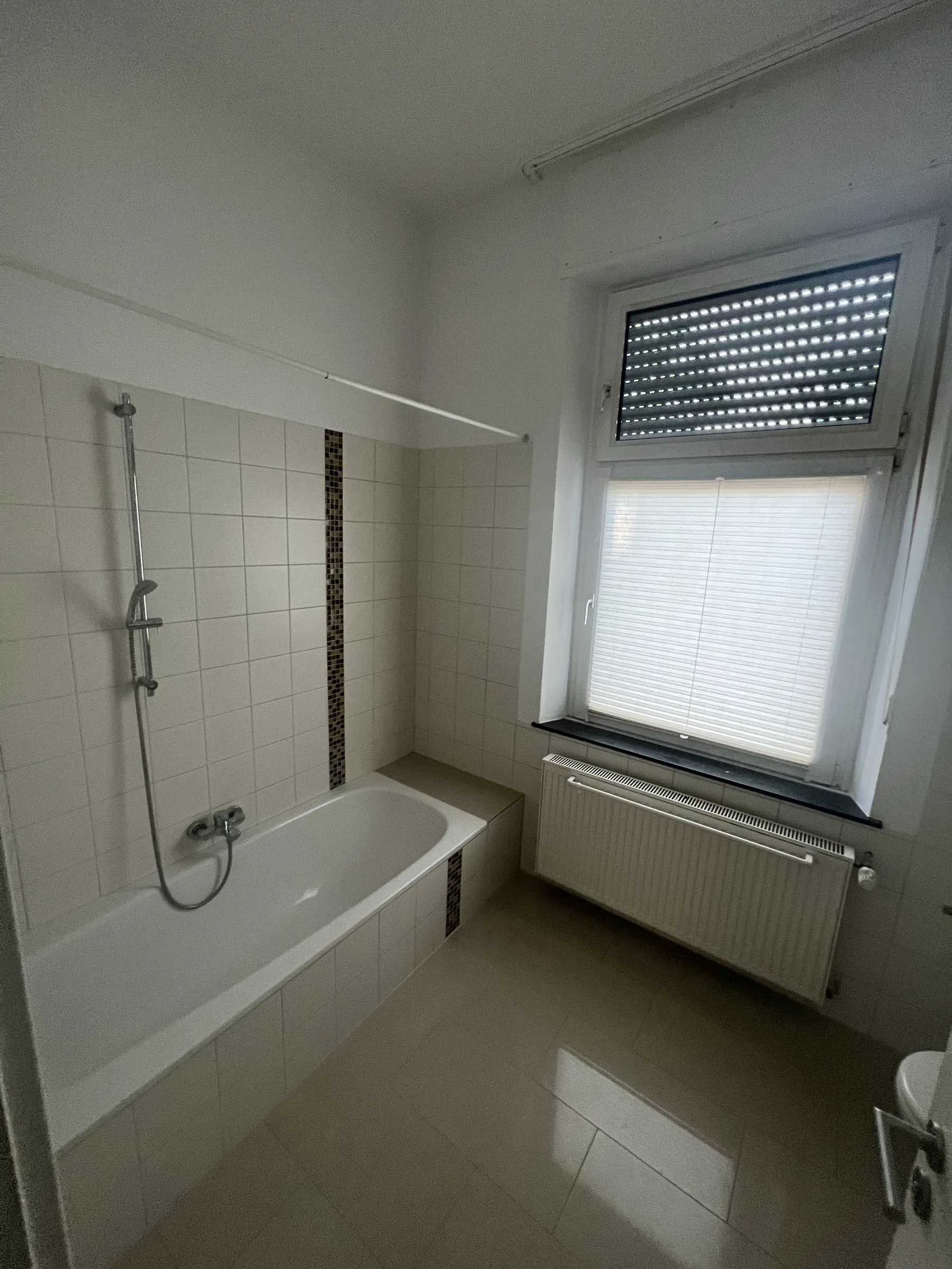 Wannenbad mit hellen Fliesen und Tageslicht durch das Badfenster