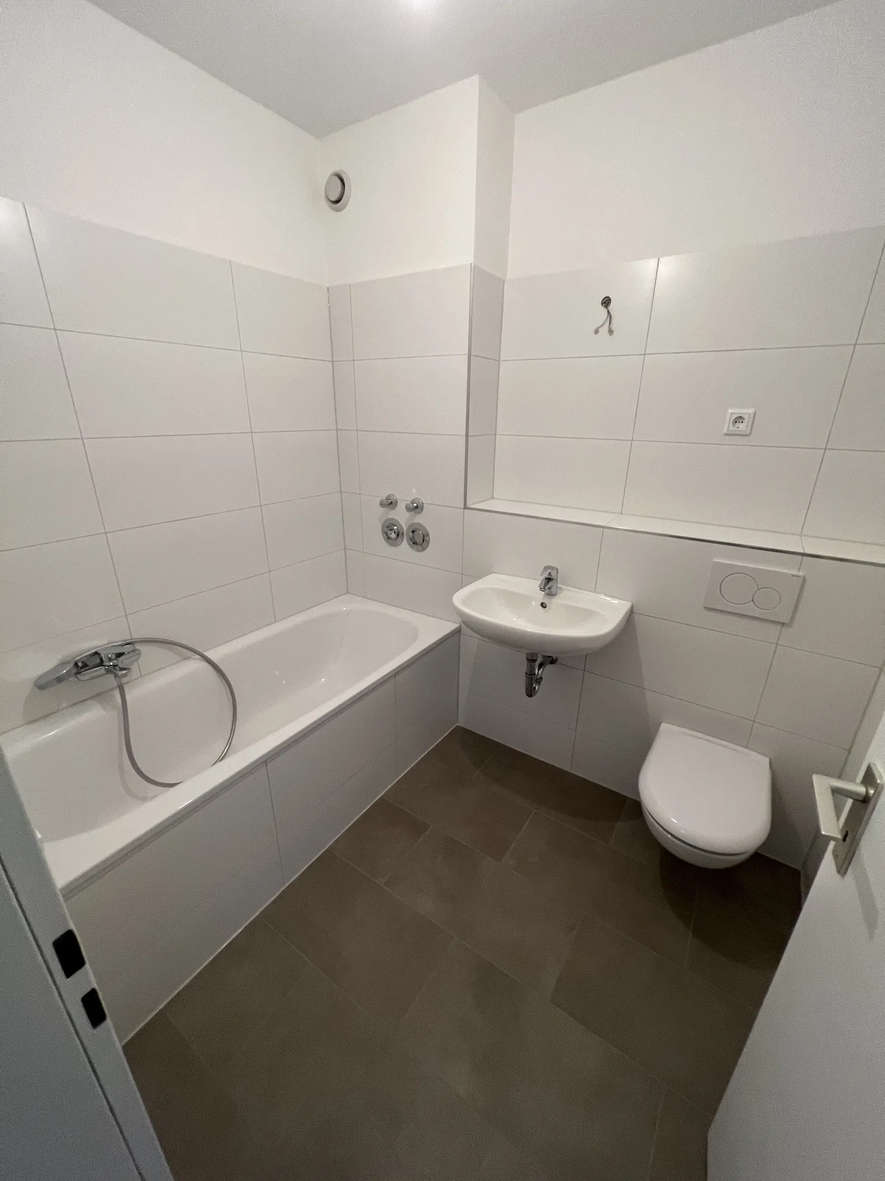 Wannenbad mit weißen Fliesen, Waschbecken und WC