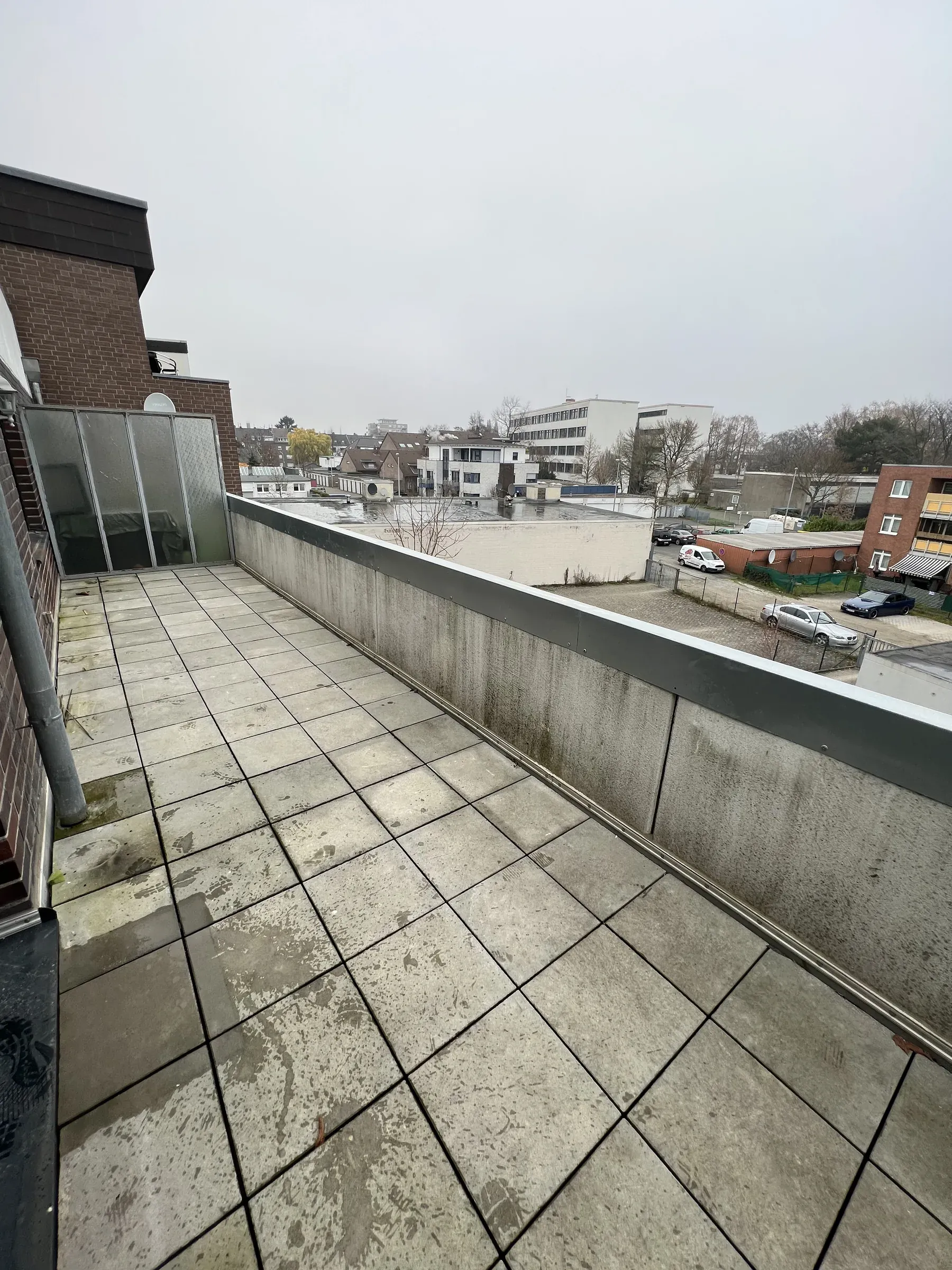 Große gefliste Dachterrasse mit Brüstung und Blick über die Nachbarbebauung